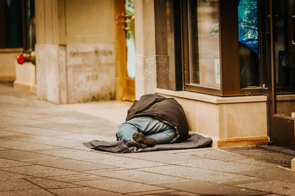 Image of a homeless guy sleeping on the sidewalk.
