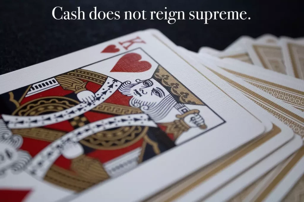 Image of the king of hearts on top of a deck of playing cards with quote: cash does not reign supreme.