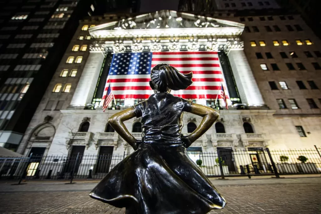 Image of Wall Street girl standing in front of the New York Stock Exchange building.
