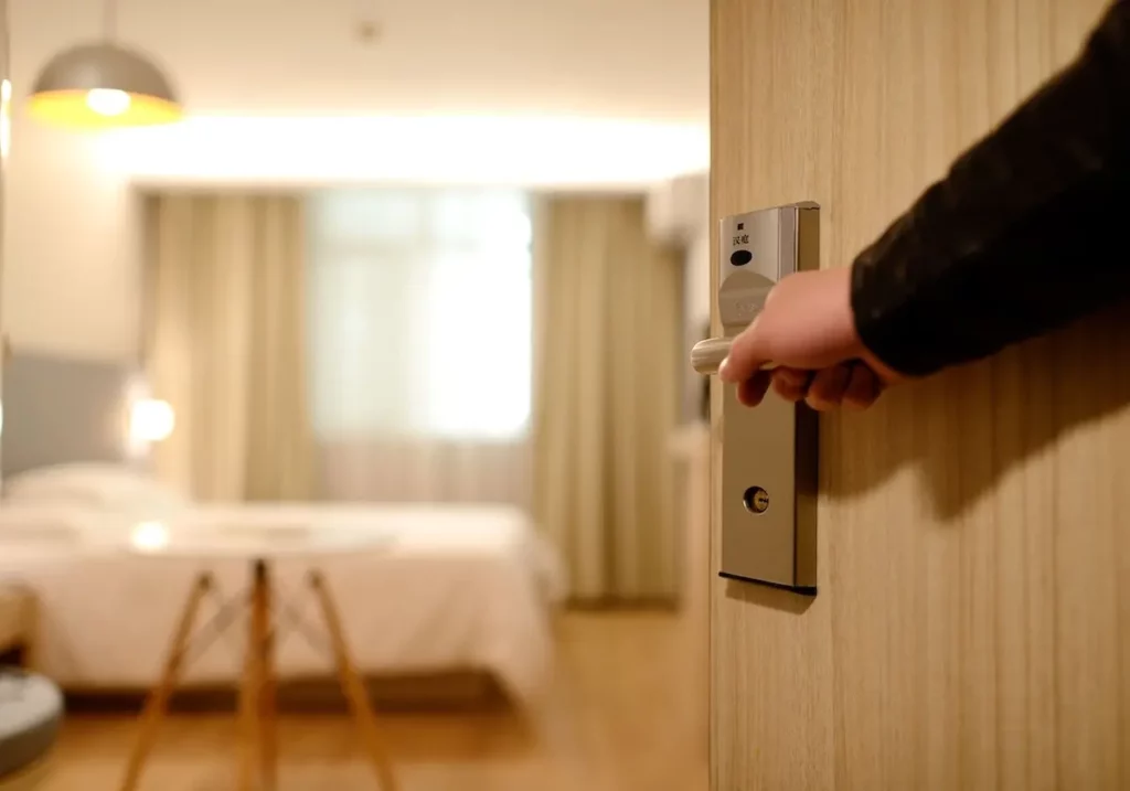 Image of a hand opening the door to a hotel room.