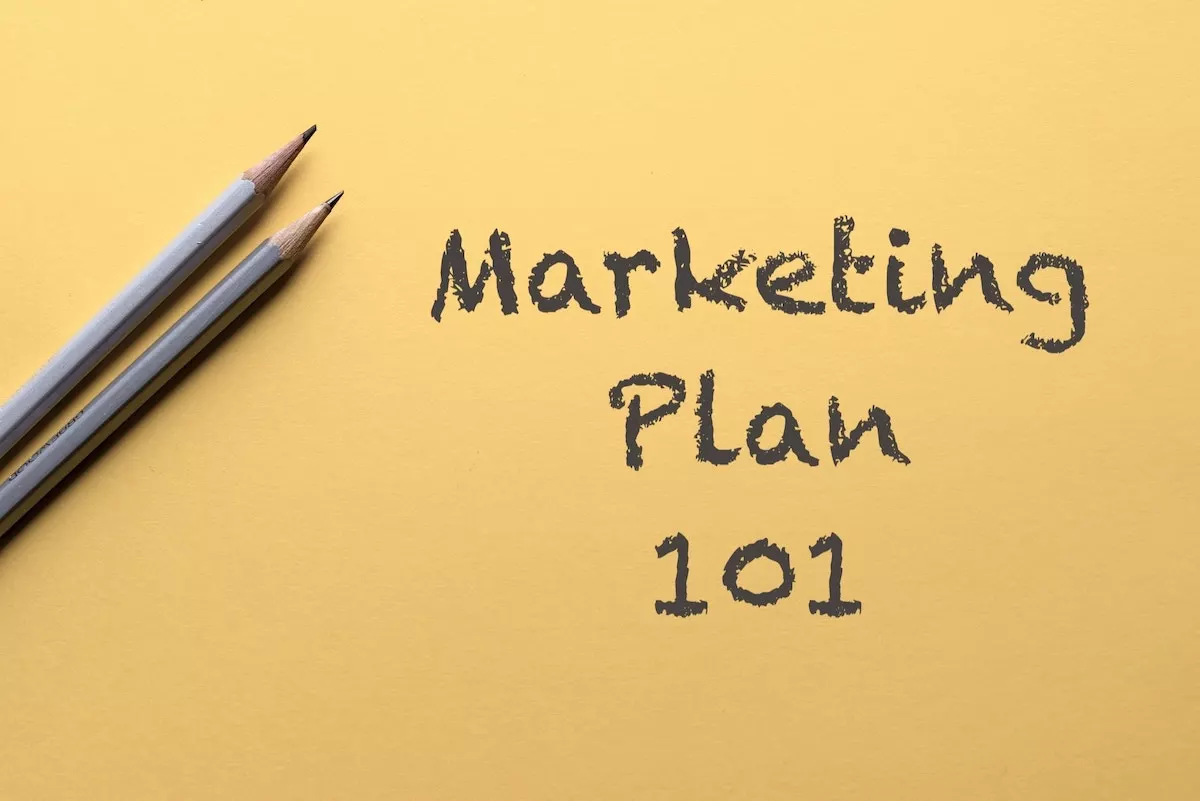Image of a couple of pencils on a piece of coloured paper with the text overlay: Marketing Plan 101