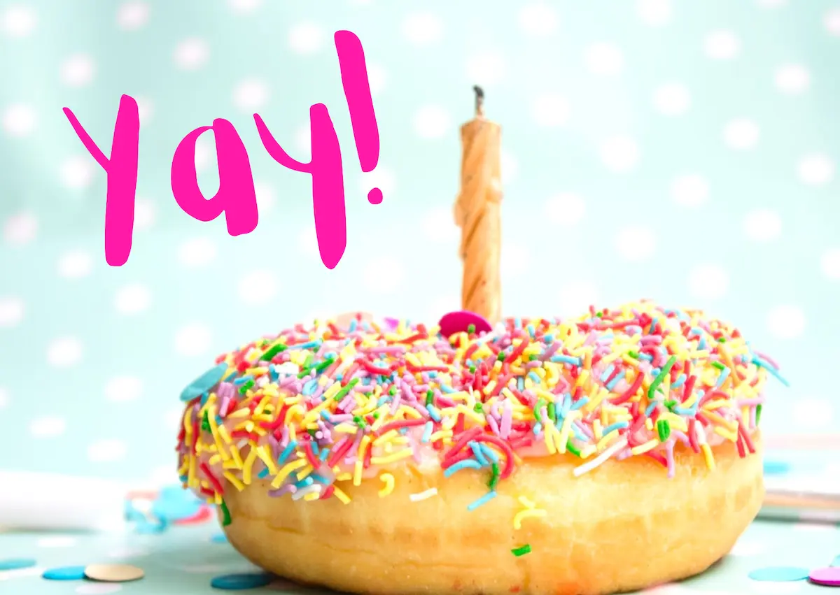 Image of a candy-coated donut with a birthday candle inserted, with the text overlay: Yay!